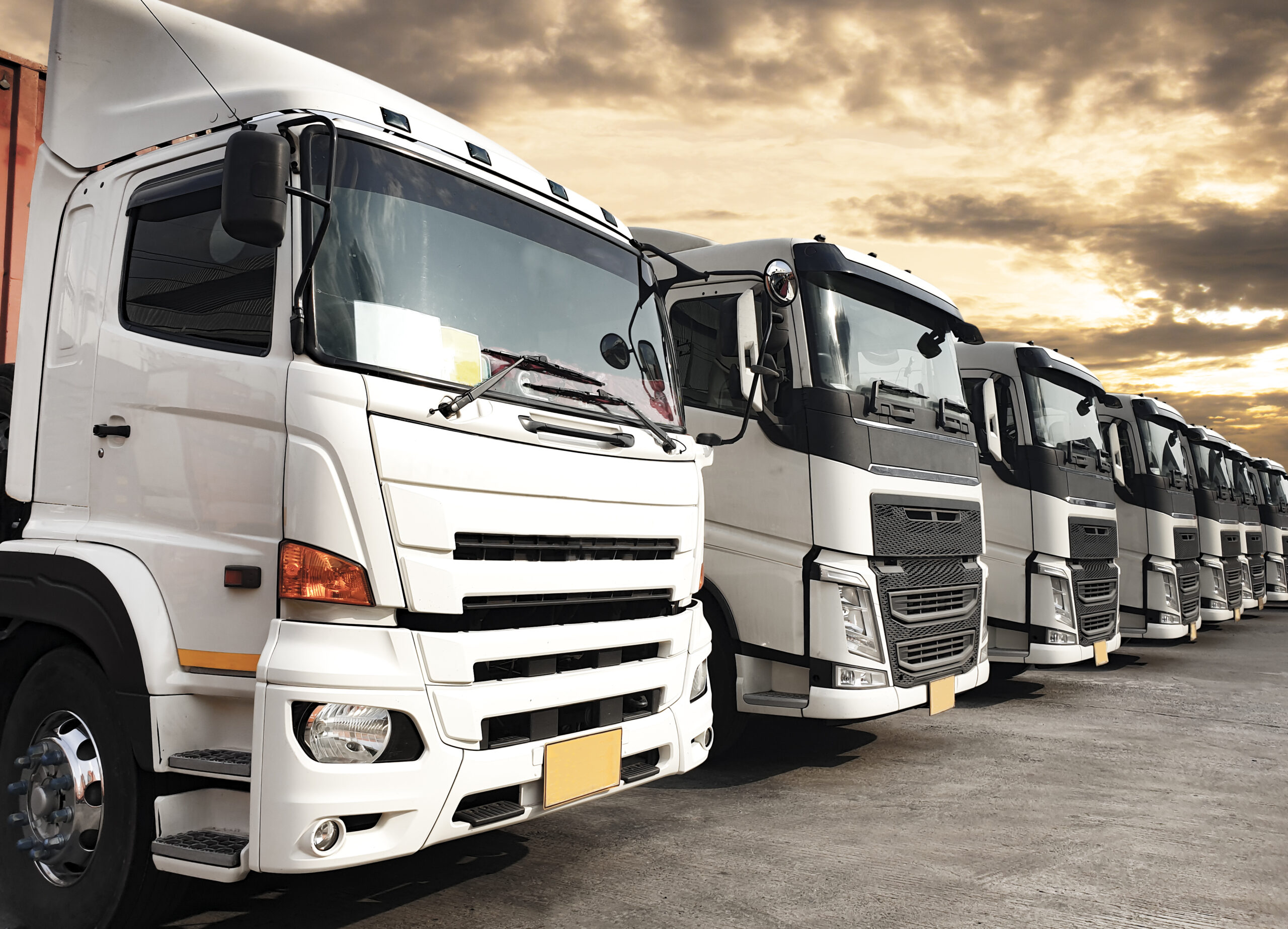 trucks-parked-lined-up-sunset-sky-road-freight-industry-logistics-transport